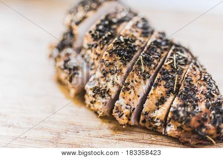 Sliced baked in spices fillet of chicken breast on a wooden cutting board