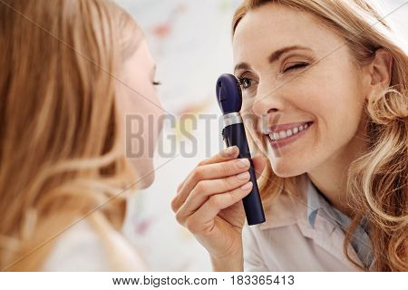 Scrupulous observations. Competent skillful young specialist employing specialized equipment while giving a consultation and looking for any sign of disease