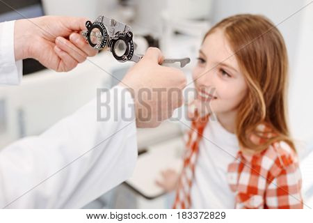 For fixing some problems. Wonderful caring scrupulous doctor giving little girl a pair of trial spectacles for indicating the right lenses and making her see things clearly again