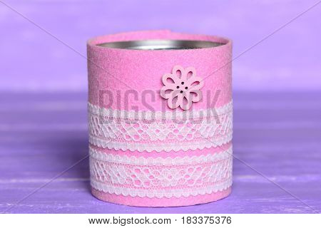 Recycled can isolated on wood background. Tin can decorated with felt, lace and flower button. Inexpensive way to make craft projects for home. Recycling tin can into organizer or planter for kitchen