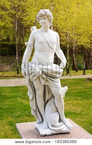 Sculpture in classic style. Statue of a man hunter with bow and dog.