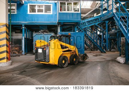 An industrial machine is driving through the plant. Waste processing plant. Recycling and storage of waste for further disposal. Business for sorting and processing of waste.