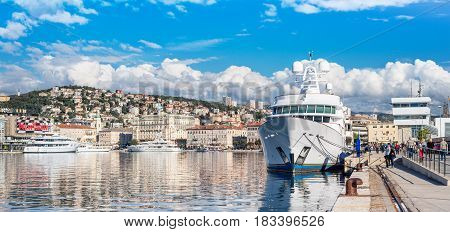 Rijeka - June of 2012 Croatia: View of Rijeka harbor, white ship at the pier, people are walking along promenade, cityscape in sunny day with blue sky and clouds