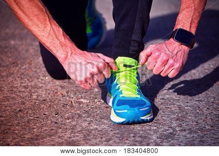 Athlete during training tying shoelaces on sneakers summer.