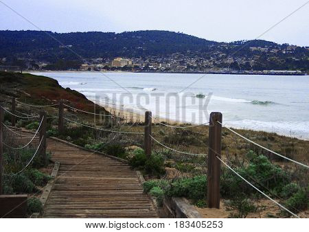 Wooden pathway leading down beach with Monterey, California in the distance
