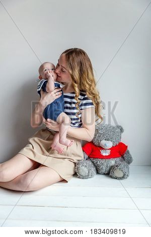 Young mother holding her newborn child. Woman and new born boy relax in a white bedroom. Mother breast feeding baby. Family at home