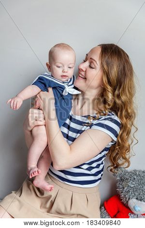 Young mother holding her newborn child. Woman and new born boy relax in a white bedroom. Mother breast feeding baby. Family at home