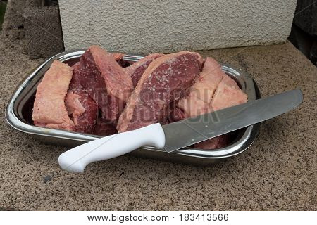 Many Cut Pieces Of Picanha Brazilian Beef With Big Knife With White Handle On A Stainless Steel Tray