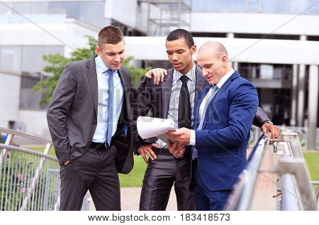 Three Businessmen Discussing Document Outside them Office
