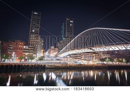 Bilbao cityscape and pedestrian zubizuri bridge at night Bilbao Basque country Spain.