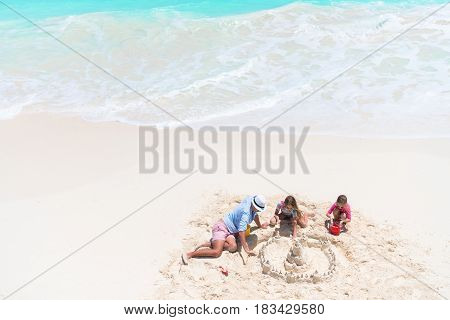 Family making sand castle at tropical white beach