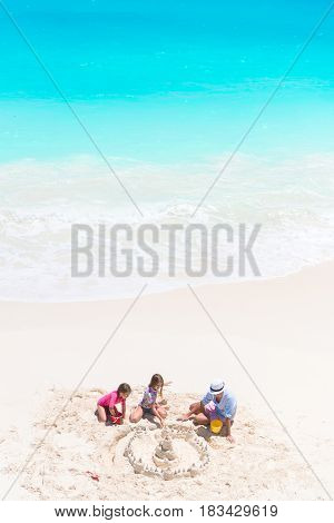 Family making sand castle at tropical white beach