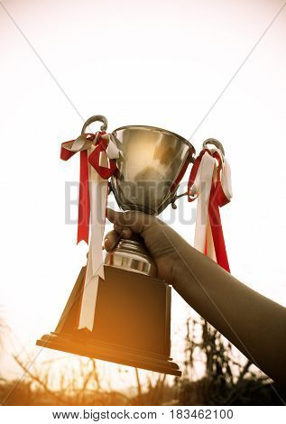 winner and champion concept Silhouette of Hand holding championship trophy against sunshine sky