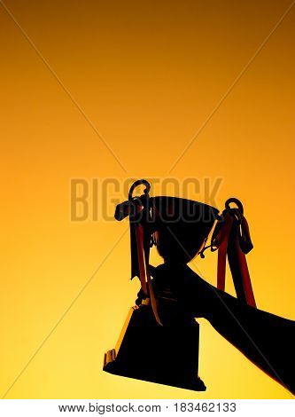 winner and champion concept Silhouette of Hand holding championship trophy against yellow sky