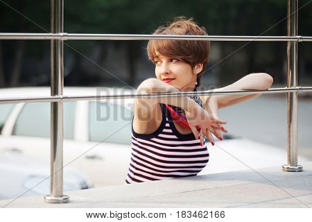 Happy young woman in city street. Stylish fashion model in tank top with pixie hairstyle outdoor
