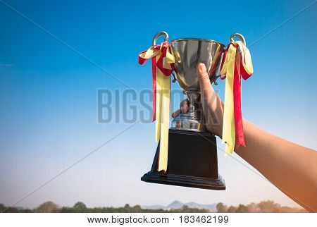 winner and champion concept Hand holding championship trophy against blue sky