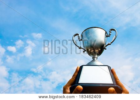 winner and champion concept Hand holding championship trophy against blue sky