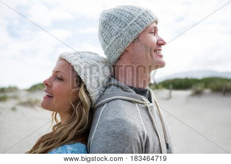 Mature couple standing back to back on beach