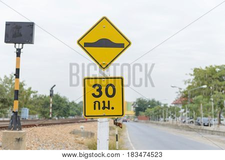 Warning sign of washboard road and Speed limit sign (30km.) in Thai language on the road