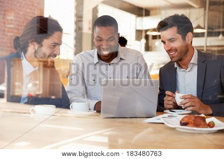 Three Businessmen Meeting In Coffee Shop Shot Through Window