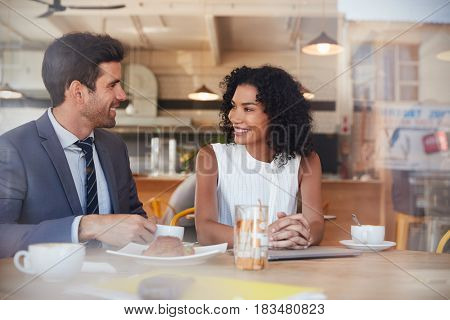 Two Businesspeople Meet In Coffee Shop Shot Through Window