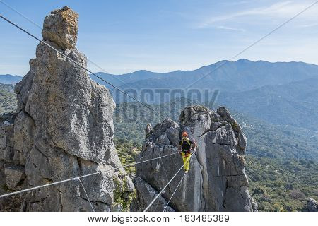 Male climber wearing special clothing and walking on rope with landscape on background