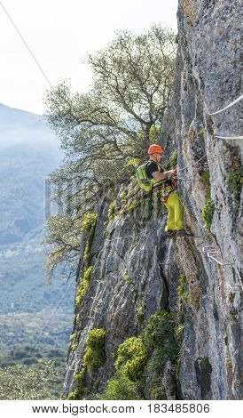 Side view of male in special clothing clinging cliff