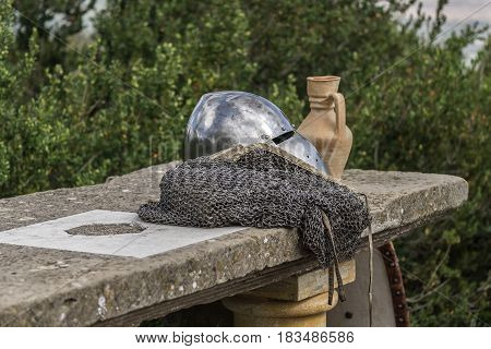 Helmet, chainmail, sword and shields on a stone table of a medieval armor knight ready for battle