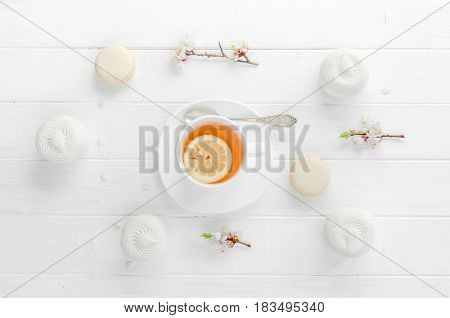Tea with lemon in white porcelain dishware, macaroons and zefir on side, topivew