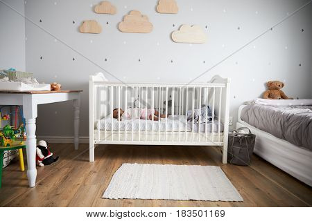 Side View Of Baby Girl Sleeping In Nursery Cot