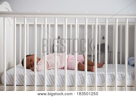 Side View Of Baby Girl Sleeping In Nursery Cot