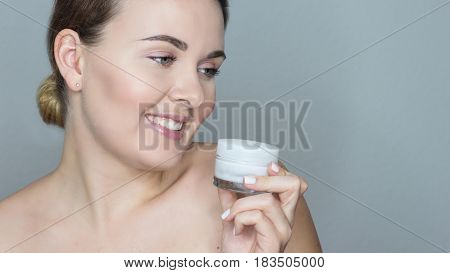 Young beautiful woman causes facial cream. Portrait of a young happy woman.