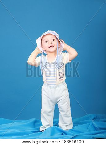Joyful little boy in a sailor suit. On a blue background