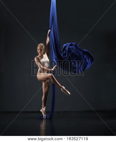 Pretty blonde in beige bodysuit and pointeshoes exercising on nice blue aerial silks