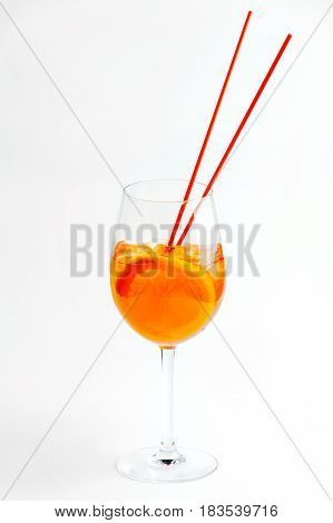 Glass of cocktail with orange and ice with a straw on white