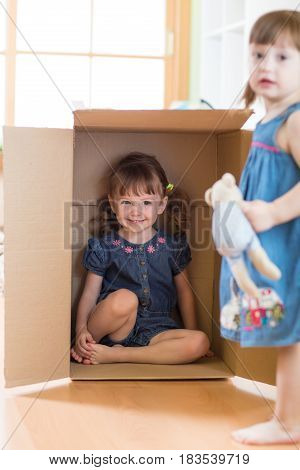 Child little girl playing and sitting inside box