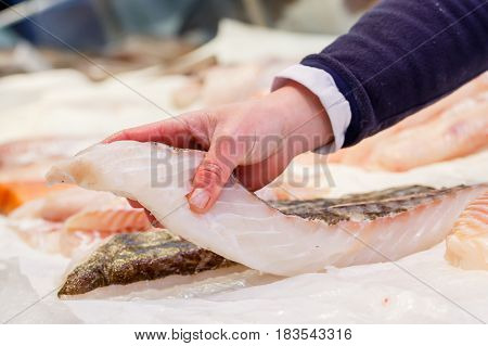 Fishmonger holding a piece of fresh fish in a market