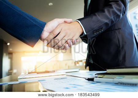 Two businessmen shaking hands during a meeting in the office success dealing greeting & business partner concepts - soft light.