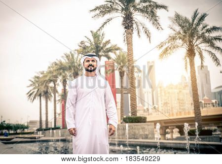 Arabic businessman walks in Dubai at sunset