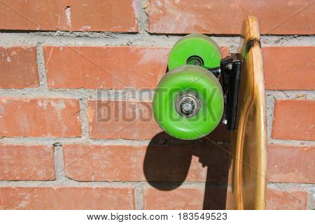 Longboard and green whels on the brick's background. Shallow depth of field. Close up.