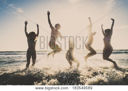 Multi-ethnic group of friends jumping on the beach - Young people having fun in the sea during summer holidays