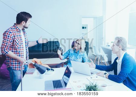 Exchange of ideas. Pleasant involved office workers working on the project and dicussing it in the office