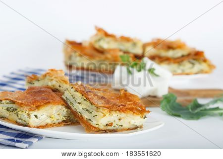 Homemade cheese and spinach pie on a white plate. Shallow depth of field.