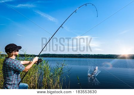Angler holds a fishing rod with a reel.