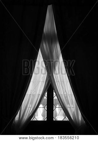 Elegant old window with curtains and drapes in a dark room