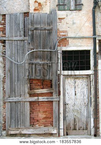 Old board up house with weathered grey planks brick walls and a white door