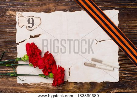 Vintage background for a victory day postcard with a red carnation two cigarettes and a 9 digit