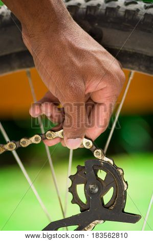 Closeup hand working on mechanical parts next to wheel spokes.