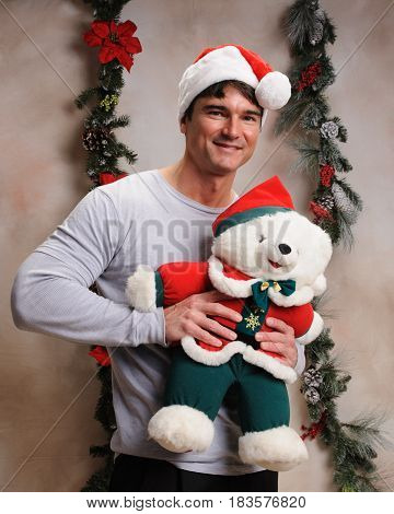 The cute lovable man is holding Christmas teddy.