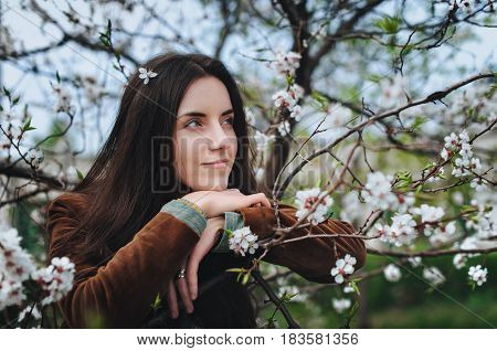 Nice girl near a blossom apricot tree in spring.